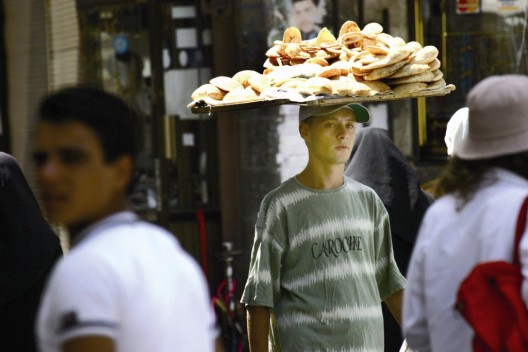 Un joven lleva una bandeja con el tradicional pan árabe en el zoco de Al Hamidiya, uno de los más antiguos del mundo árabe