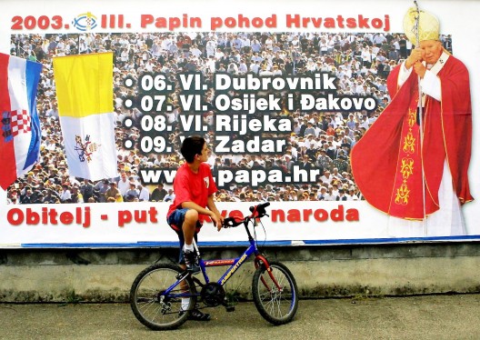 Un niño croata observa un cartel anunciando el tour del Papa Juan Pablo II